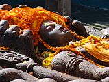 Kathmandu Valley 1 Budhanikantha 3 Sleeping Vishnu Head Close Up Budhanilkantha Narayan (Sleeping Vishnu) lies peacefully on the coils of the multi-headed snake Ananta. The snakes 11 hooded heads rise protectively around Narayans head. Vishnus four hands hold the four symbols of Vishnu: chakra disk(representing the mind), a conch shell (the four elements), a mace (primeval knowledge), and a lotus seed (the moving universe).
